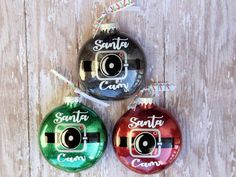 three christmas ornaments with the words santa and camera on them