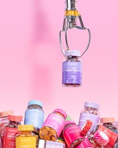 a bunch of jars that are hanging from a light fixture in front of a pink background