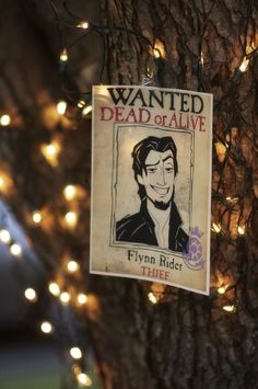 a wanted dead or alive sign hanging from a tree with lights around it on the side