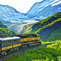 a yellow and black train traveling through mountains