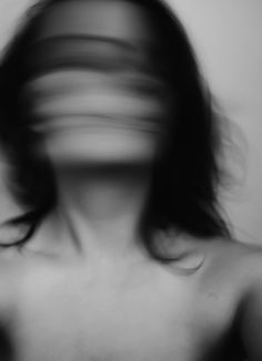 a blurry image of a woman's face with her hair blowing in the wind