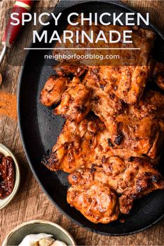 chicken wings in a skillet with sauces and seasoning on the side for garnish