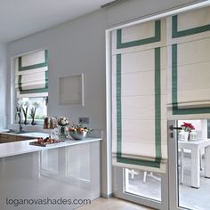 a kitchen with white counter tops and green striped blinds on the window sills