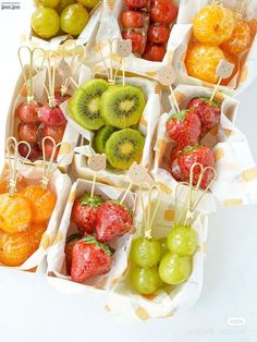 there are many different fruits in the trays on this white tablecloth, including kiwis and oranges