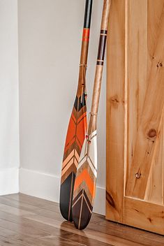 two paddles leaning up against a wall in front of a wooden door and floor