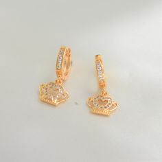 Dangle in regal delight with our Crown Earrings, a masterpiece of elegance and charm. Embrace timeless sophistication and radiate confidence with every sway. The crown symbol jewel represents glory, power, immortality, royalty and sovereignty. 14K Gold Plating Suitable for daily wear Light weight Hypoallergenic Nickel free Waterproof Tarnish Resistant Maintenance Tips: To keep our products in top-notch condition, we recommend avoiding contact with substances such as perfumes, hairsprays, and lot Regal Gold Jewelry With Crown Design, Cubic Zirconia Crystal Earrings For Celebration, Classic Gold Crown Jewelry, Elegant Yellow Gold Jewelry With Crown Design, Elegant Yellow Gold Crown Design Jewelry, Elegant Huggie Earrings For Gift, Elegant Gold Jewelry With Crown Design, Elegant Gold Crown Design Jewelry, Regal Gold Jewelry For Anniversary