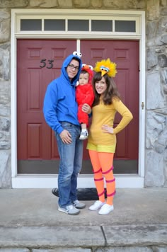 a man and woman are standing in front of a red door with their child wearing costumes