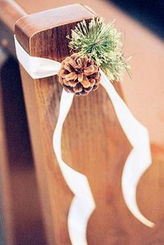 a pine cone tied to the back of a church pew with a white ribbon around it