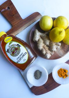 some lemons, ginger and other spices on a cutting board next to a bottle of ketchup