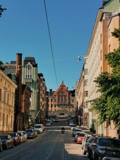 cars parked on the side of a street next to tall buildings and power lines above them