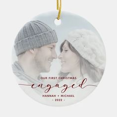 a christmas ornament with an image of two people in winter hats and the words engaged on it