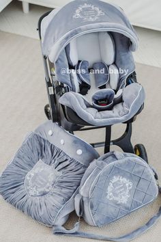 a baby stroller with several items in it sitting on the floor next to a bed