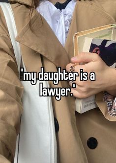 a woman wearing a trench coat and holding a book in her hand with the words, my daughter is a lawer