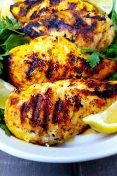 grilled chicken with lemon and parsley on a white plate