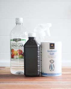 two bottles of vinegar, an empty canister and a bottle of salt on a wooden table