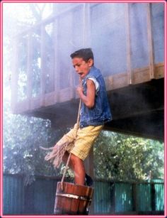 a young boy is holding a bucket and talking on the phone