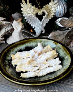 powdered sugar sticks on a plate next to christmas decorations and angel figurines