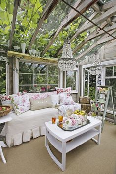 a living room filled with furniture and lots of windows covered in greenery next to a white couch