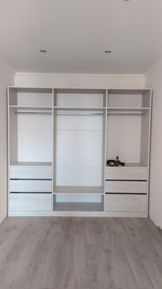 an empty room with white shelves and drawers