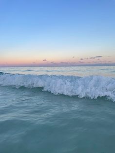 the ocean waves are crashing into the shore at sunset or dawn, as seen from the water's edge