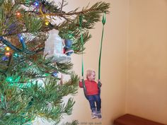 a young child hanging from a christmas tree