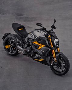 a black and yellow motorcycle parked in a parking lot next to some concrete flooring