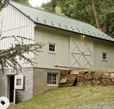 an old barn with a green roof sits in the woods