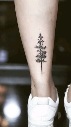 a small pine tree tattoo on the left leg and right calf area is shown in black ink