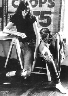 a woman sitting on top of a wooden chair next to a man standing behind her