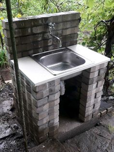 a sink built into the side of a brick wall with a faucet attached to it