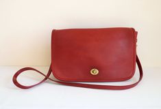 "Coach Convertible Clutch bag in patina'd red leather.  This iconic Coach bag is high quality featuring a clean interior, flap turn lock closure, front pocket, and small interior compartment with zipper. The Coach Convertible Clutch has been throughly cleaned, conditioned, and hardware polished.  In good condition with expected wear, patina and imperfections. Imperfections include minor exterior blemishes, pen marking under the flap, and pen markings on the interior and suede areas - please revi Classic Red Flap Bag With Magnetic Closure, Classic Red Flap Bag With Removable Pouch, Classic Red Flap Bag, Timeless Red Satchel For Everyday Use, Red Timeless Satchel For Everyday Use, Timeless Red Satchel, Contemporary Costumes, Basic Jewelry, Coach Bag