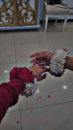 two people reaching out to each other with flowers in their hands and petals on the floor