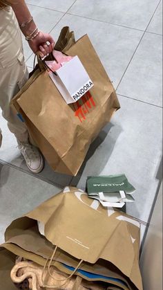 a person is holding some paper bags on the floor