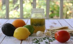 an assortment of fruits and vegetables sitting on a wooden table next to a mason jar