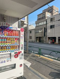 a vending machine is on the side of the road with buildings in the background