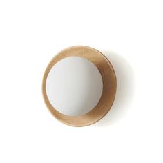 a round mirror mounted to the side of a wall next to a wooden frame on a white wall