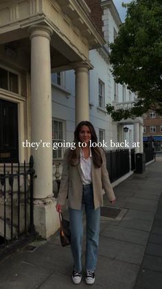 a woman is walking down the sidewalk with her hand in her pocket