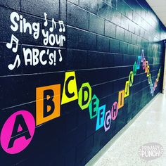 a school hallway with black wall and colorful letters painted on the wall, along with music notes