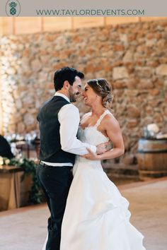 a bride and groom sharing their first dance at the wedding reception in front of an old stone wall