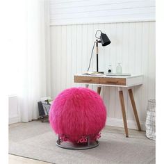 a bright pink pouffle sits in front of a desk with a lamp on it