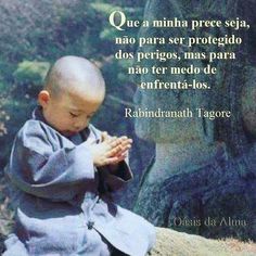 a little boy sitting on top of a rock next to a buddha statue and praying