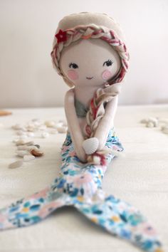 a little doll sitting on top of a bed next to a starfish toy and shells