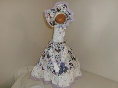 the doll is wearing a dress with flowers on it and a wooden ball in its mouth