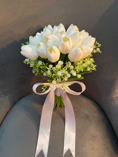 a bouquet of white tulips and baby's breath tied to a chair