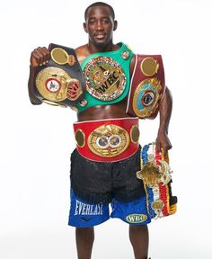 a man holding two boxing gloves and a belt in his right hand while standing next to each other