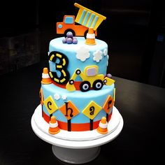 a blue and orange cake with construction vehicles on it