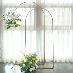 two vases with flowers are on display in front of a window and sheer curtains