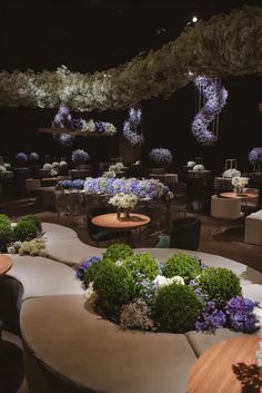 a room filled with lots of tables and chairs covered in purple and white flower arrangements