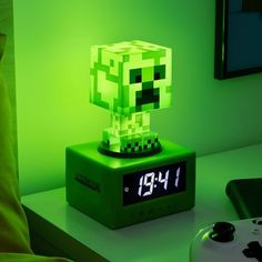 a green alarm clock sitting on top of a table next to a video game controller