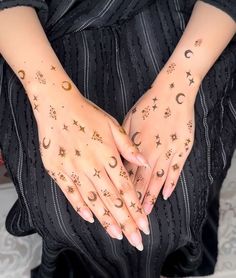 a woman's hands with stars and moon tattoos on them